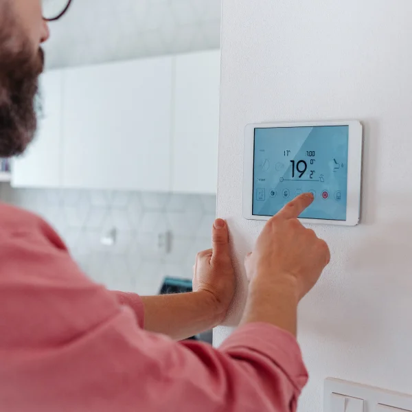 Un hombre ajusta la temperatura de un termostato inteligente para controlar el clima en su hogar.