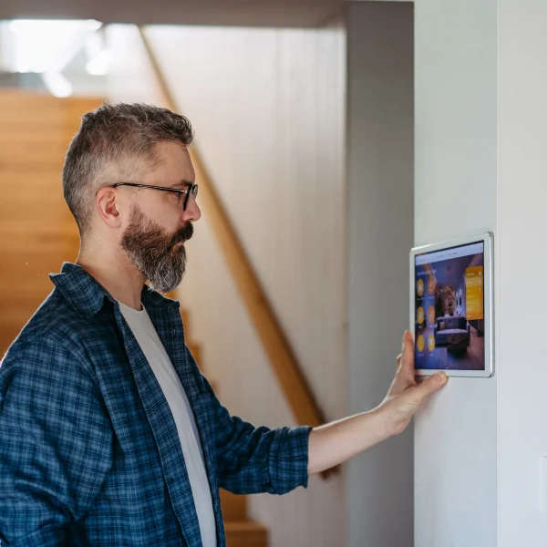 Un hombre sostiene una tableta frente a una pared con iluminación inteligente.