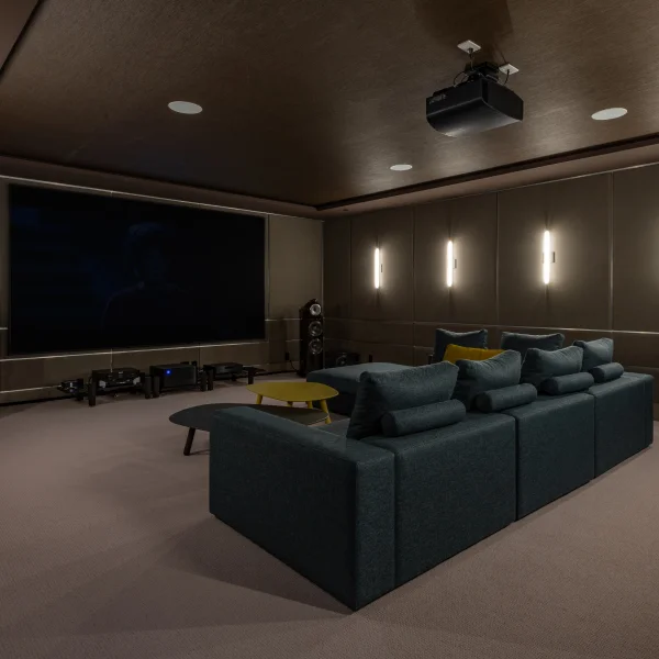 Sala de cine en casa con un sofá cómodo y un proyector para disfrutar de películas.